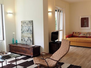 A living room with a sofa, a television, a coffee table, and a painting.