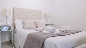 A neatly made bed with a tufted headboard, two bedside tables with lamps, and a mirror. - Family Getaway with Pool in Southern Crete (Lagkada)
