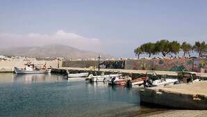 A harbor with boats docked, a concrete breakwater, and a mural on the wall. - Family Getaway with Pool in Southern Crete (Lagkada)