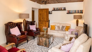 Un salon avec un plafond en bois, un lustre, une cheminée, une bibliothèque et une table basse.