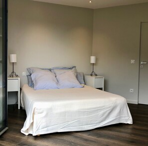 Une chambre à coucher avec un lit, deux tables de chevet et une porte.