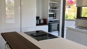 Una cucina moderna con mobili bianchi, un piano di lavoro in legno scuro e un piano cottura integrato.