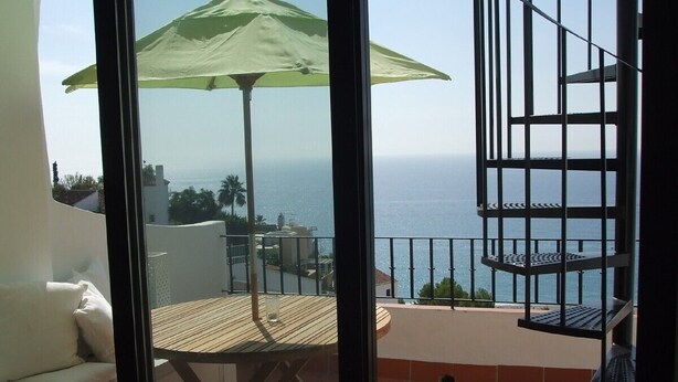 Ein Balkon mit Tisch, Stühlen und einem grünen Sonnenschirm.