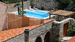 Un edificio de piedra con piscina, mobiliario exterior y un pérgola.