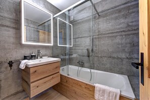 A modern bathroom with a wooden vanity, a large mirror, and a glass-enclosed shower.