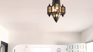 Cocina compacta con microondas, estufa y lavaplatos. Hay dos taburetes de bar y una mesa roja.