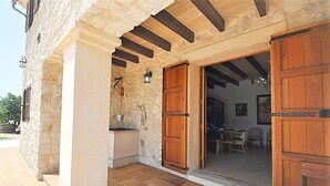 A stone building with wooden doors and a tiled patio.