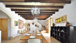 A dining area with a long wooden table set for a meal, a chandelier, and a staircase leading to an upper level.