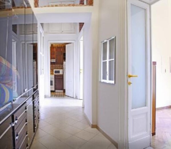 Corridor leading to a kitchen area with a door and cabinets in view.