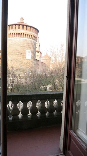 A view of a historic stone tower through a window with a balustrade.