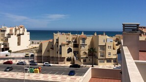 A coastal residential area with buildings, a parking lot, and a view of the sea.