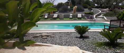 A pool area with lounge chairs and a stone pathway.