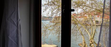 A view through a window with a view of a body of water, a dock, and trees.
