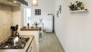Une cuisine moderne équipée d’une cuisinière à gaz, d’une bouilloire et d’un luminaire suspendu.