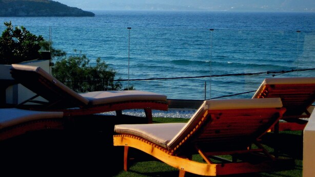 A seaside view with two wooden lounge chairs facing the ocean. - Floor apartment with superb roof terrace, next to Almirida sandy beach   (Chania)