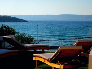 A seaside view with two wooden lounge chairs facing the ocean.