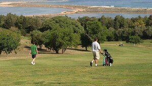 A golf course with a view of the sea and trees in the background.