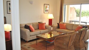 A living room with two sofas, a coffee table, and wicker chairs. There are two lamps on side tables.