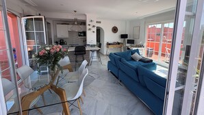 A modern living space with a dining area, a sofa, and a kitchen in the background. - BEAUTIFUL PENTHOUSE DIRECT PRIVATE  BEACH 4 BEDS (Marbella)