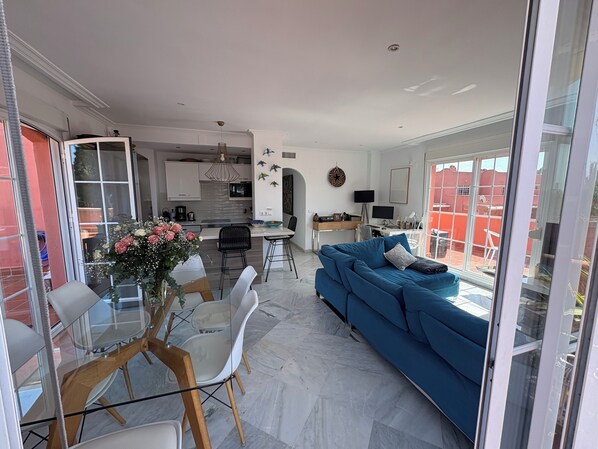 A modern living space with a dining area, a sofa, and a kitchen in the background. - BEAUTIFUL PENTHOUSE DIRECT PRIVATE  BEACH 4 BEDS (Marbella)