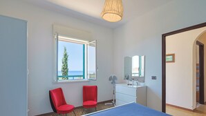 A hotel room with a bed, two red chairs, a white dresser, a mirror, and a window with a view of the sea. - House / Villa - Sciacca (Sciacca)