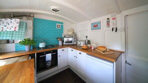 A compact kitchen with white cabinets, a blue tiled backsplash, and a wooden countertop. - Charming Seaside Home, Full of Character (Old railway carriages) Pet Friendly,  (Chichester)