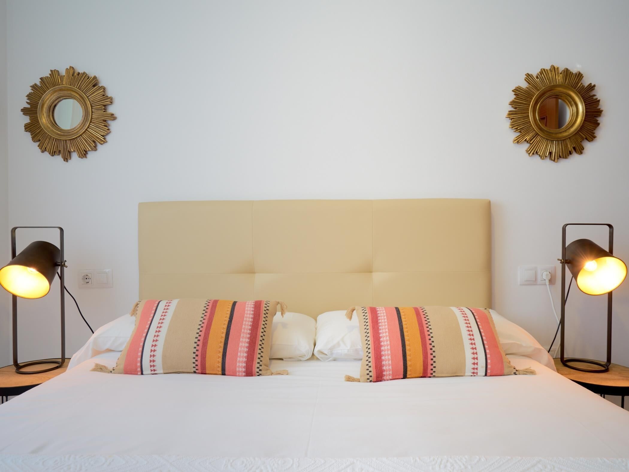 Ein Hotelzimmer mit einem großen Bett, zwei Nachttischlampen und zwei Wandspiegeln.