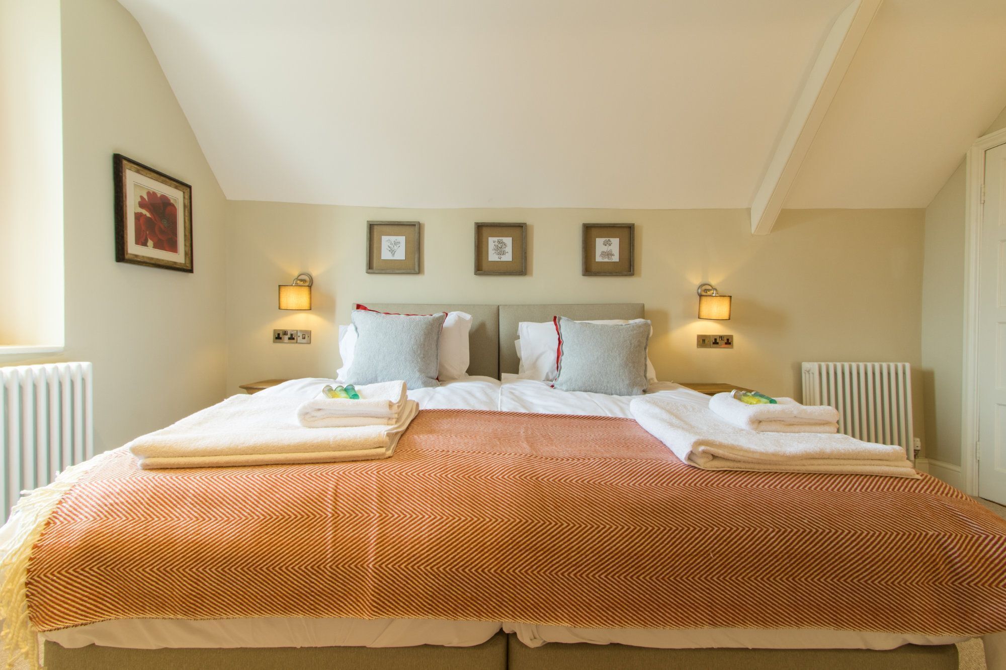 A neatly made bed with a patterned bedspread, two pillows, and folded towels.