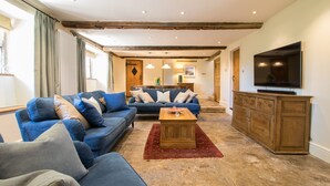 Un salon avec un canapé bleu, une table basse en bois et un téléviseur posé sur un meuble en bois.