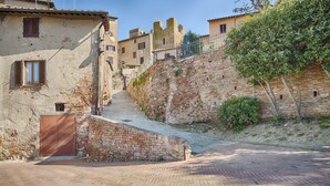 A narrow cobblestone street in a historic town with stone walls, a gate, and buildings with traditional architecture. - Tognazzi Holiday House - Casa Giglio - Medieval village of Certaldo Alto (Certaldo)