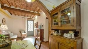 A rustic kitchen with wooden cabinets, a dining table with a placemat, and a wicker chair. - Tognazzi Holiday House - Casa Giglio - Medieval village of Certaldo Alto (Certaldo)