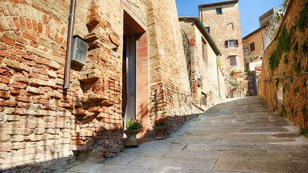 A narrow stone-paved street flanked by historic brick buildings with arched doorways and small windows. - Tognazzi Holiday House - Casa Giglio - Medieval village of Certaldo Alto (Certaldo)