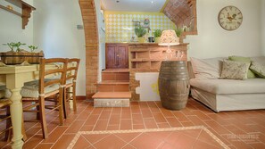 Una sala de estar acogedora con una mesa de comedor de madera, sillas, un sofá y un barril rústico.