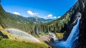 Een waterval, omringd door dicht bos en bergen.