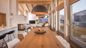 Een modern interieur met een houten eettafel, witte banken en een open haard.