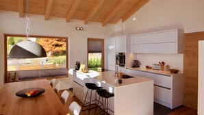 Een moderne keuken met een groot eiland, witte kastjes en uitzicht op het buitengebied.