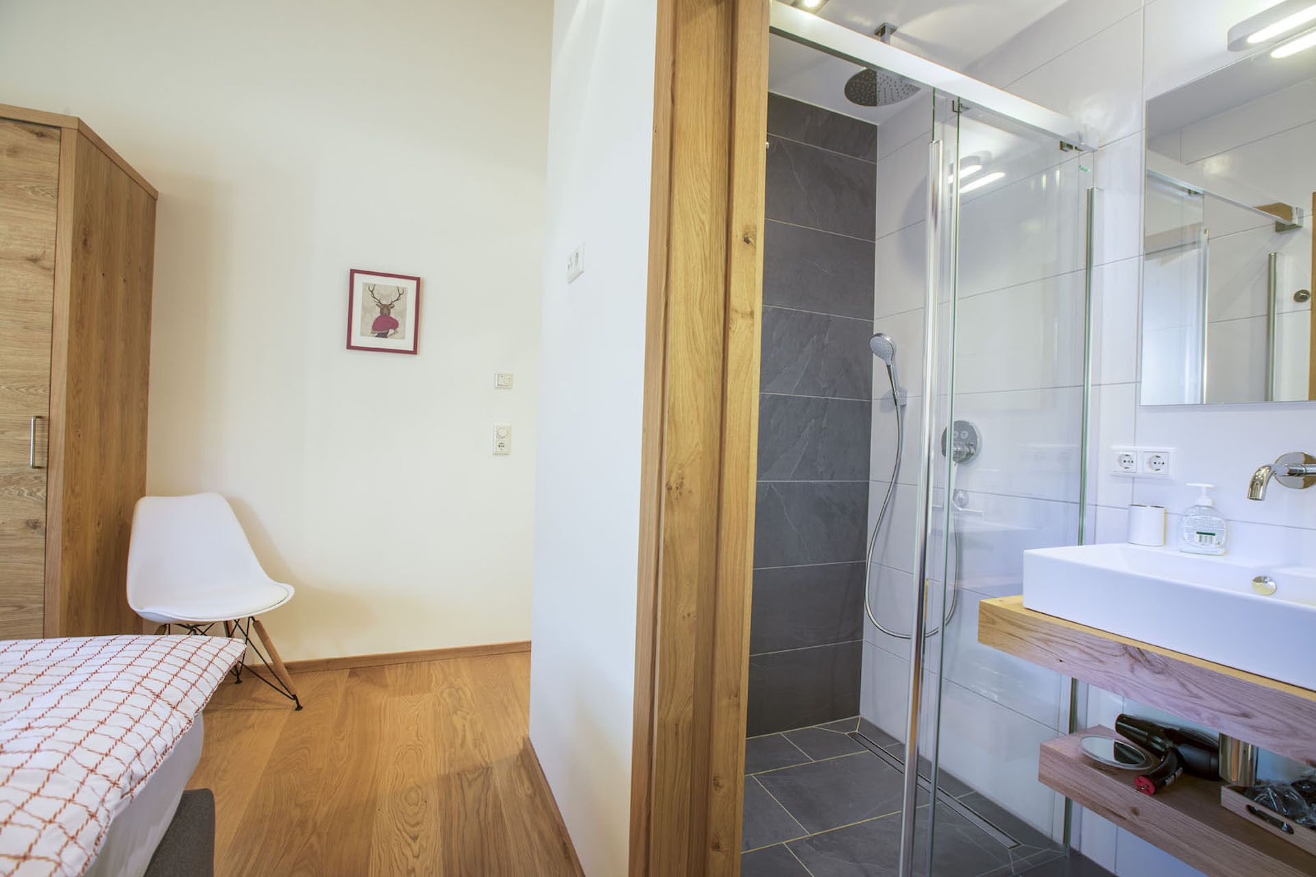 A modern bathroom with a glass shower enclosure, a white sink, and a wooden vanity.