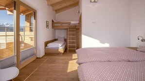 Een kamer met een stapelbed, een bureau en uitzicht op een berg.