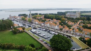An aerial view of a riverside town with historic buildings, a church, and a marina with boats. - Studio Havenzicht on top location in the historic town of Veere (Veere)