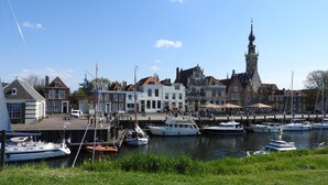 A marina with boats docked, a prominent tower, and traditional buildings with gabled roofs. - Studio Havenzicht on top location in the historic town of Veere (Veere)