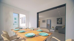 Un coin repas avec une table en bois dressée pour quatre personnes, entourée de chaises en osier.