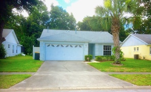 A single-story house with a garage, a front lawn, and a palm tree.