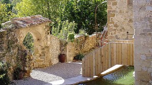 A stone archway, wooden deck, and a small pool in a garden setting. - Rural house for exclusive rental in Girona (Cabanelles)