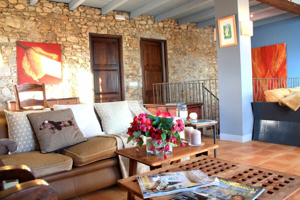 A cozy living room with a stone wall, wooden furniture, and a vase of flowers.