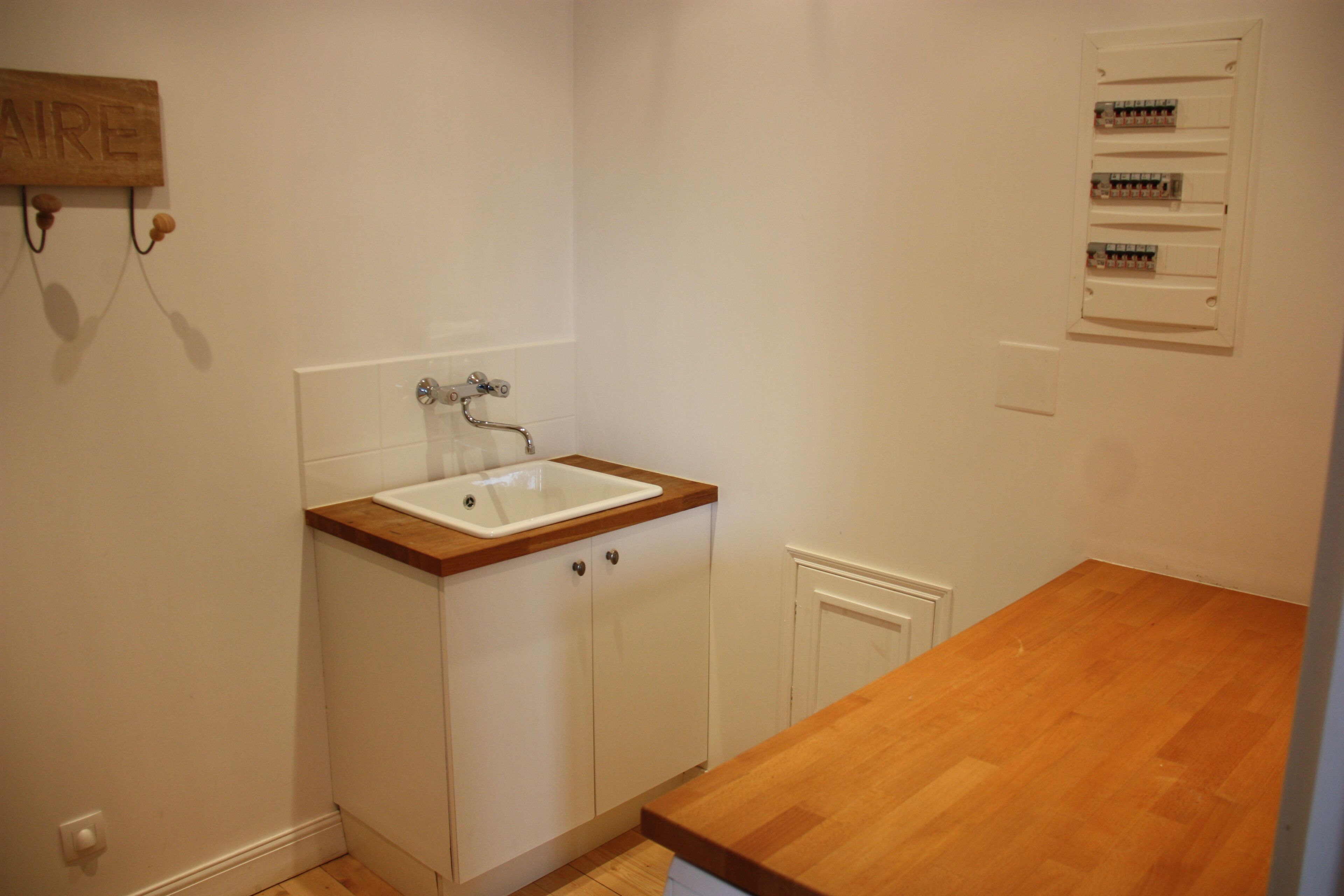 A kitchen with a wooden countertop, white cabinets, and a white sink.