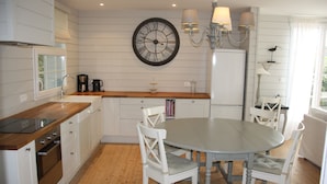 A kitchen with white cabinetry, a wooden countertop, a round dining table, and chairs. There is a clock on the wall and a chandelier above the table.