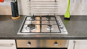 A kitchen with a gas stove, oven, and a knife block on the counter.