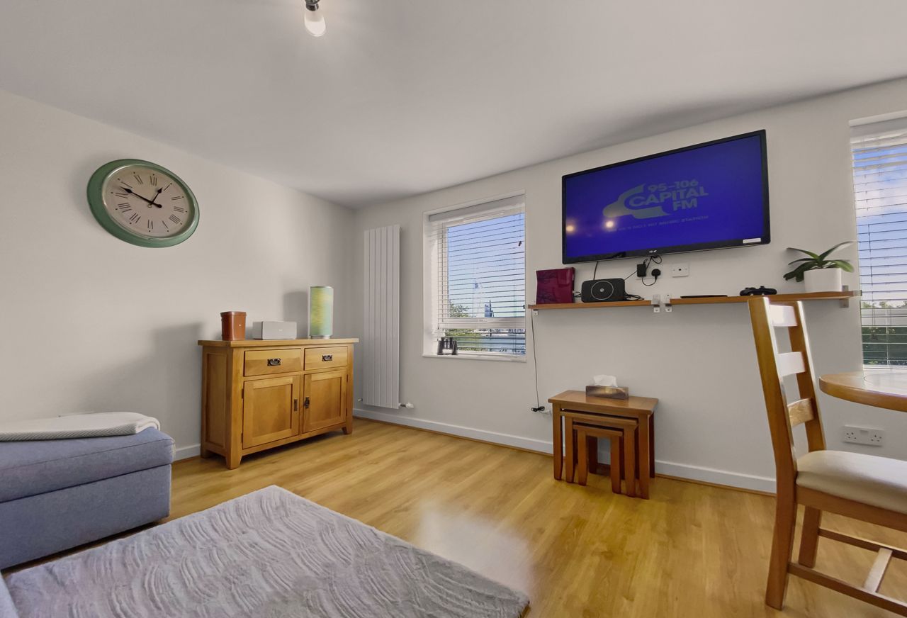 Ein modernes Wohnzimmer mit einer Couch, einem Holzschrank, einem Fernseher und einem kleinen Tisch.
