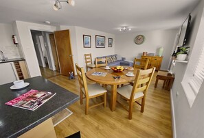 Une cuisine moderne avec un coin repas, des meubles en bois et une horloge au mur.