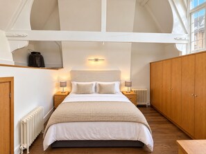 A bedroom with a large bed, two bedside tables, a radiator, and wooden wardrobes. - A unique apartment in the heart of central London. (London)